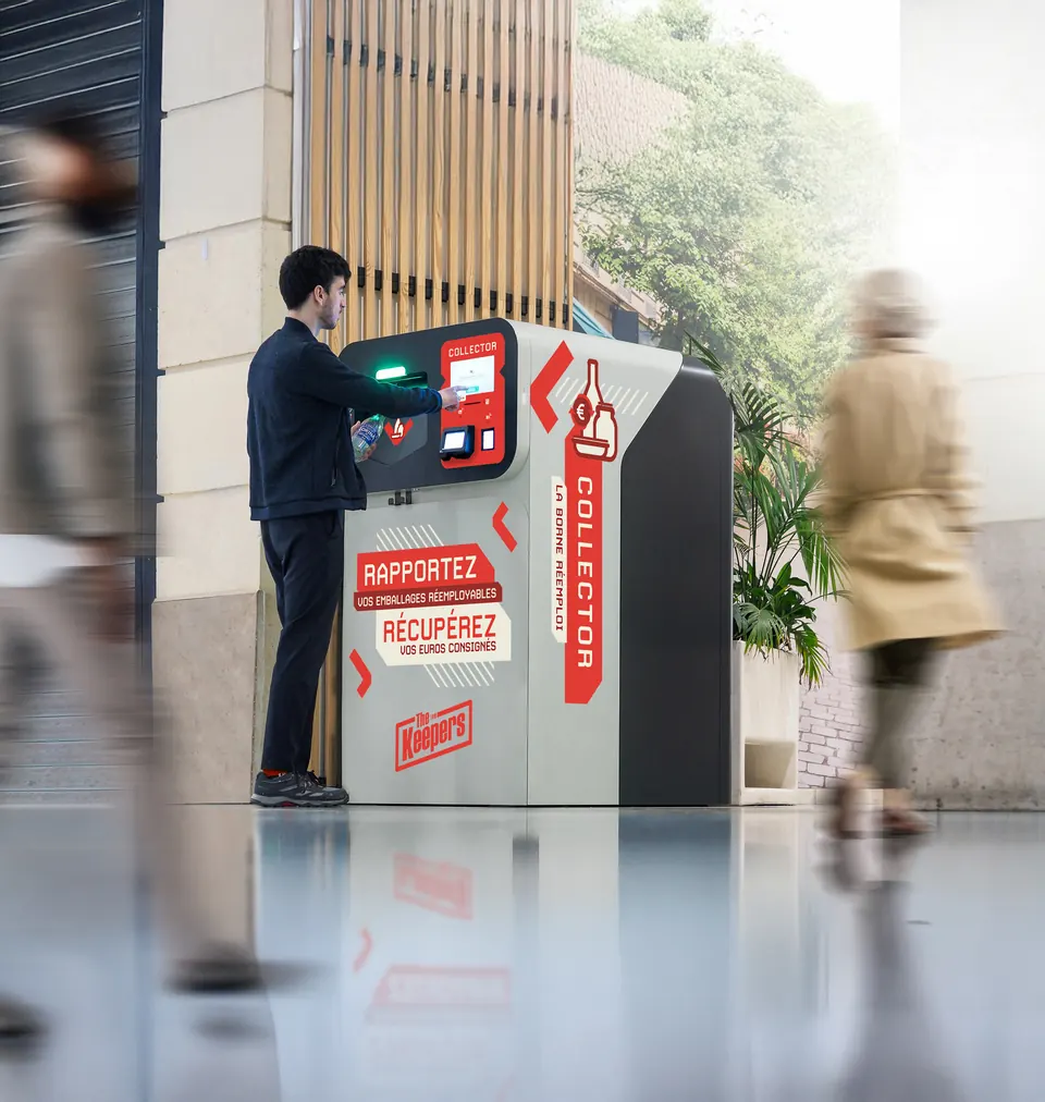 Un client dépose un emballage réemployable dans le Collector, borne de déconsignation installée à l'entrée d'un magasin