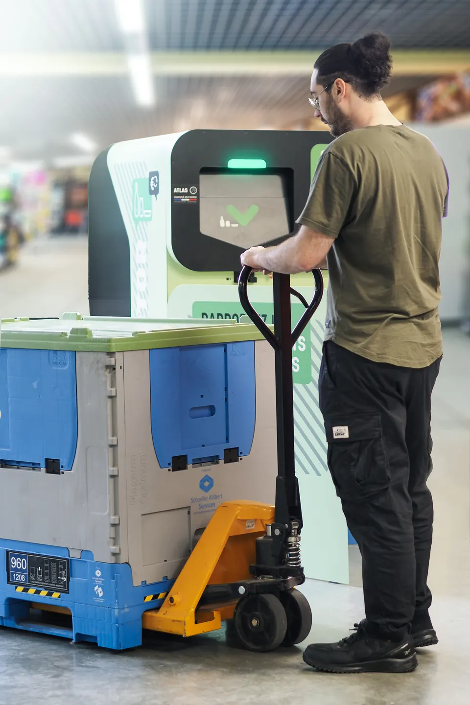 Un employé remplace la caisse-palette pleine du Collector avec un transpalette manuel